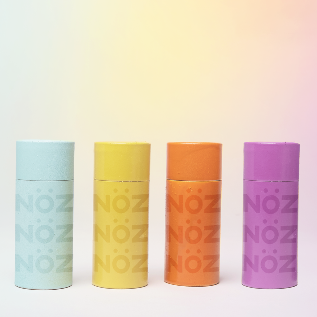 NOZ mineral sunscreen stick in blue, yellow, orange, and purple shades.